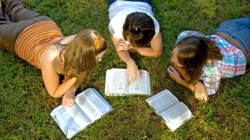 People laying outside doing a bible study. 